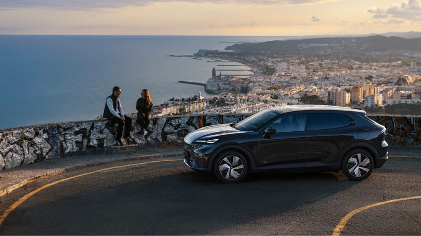 Changan Deepal S05 preto estacionado num miradouro com vista panorâmica para o mar e uma cidade costeira ao fim da tarde